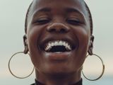 black woman with shirt hair laughing with hoop earrings with hair and dark nails