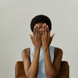 black woman covering face in blue leotard