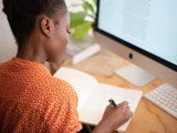 black woman making notes from computer