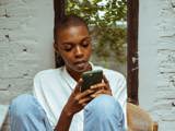 black woman with short hair on chair with green phone