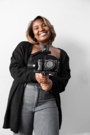 black woman in black cardigan holding a camera