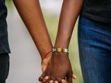 two black people holding hands with African beads