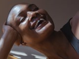 black bald woman laughing with hand on head
