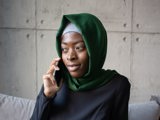 muslim woman sitting with green and grey head scarf on phone