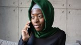 muslim woman sitting with green and grey head scarf on phone